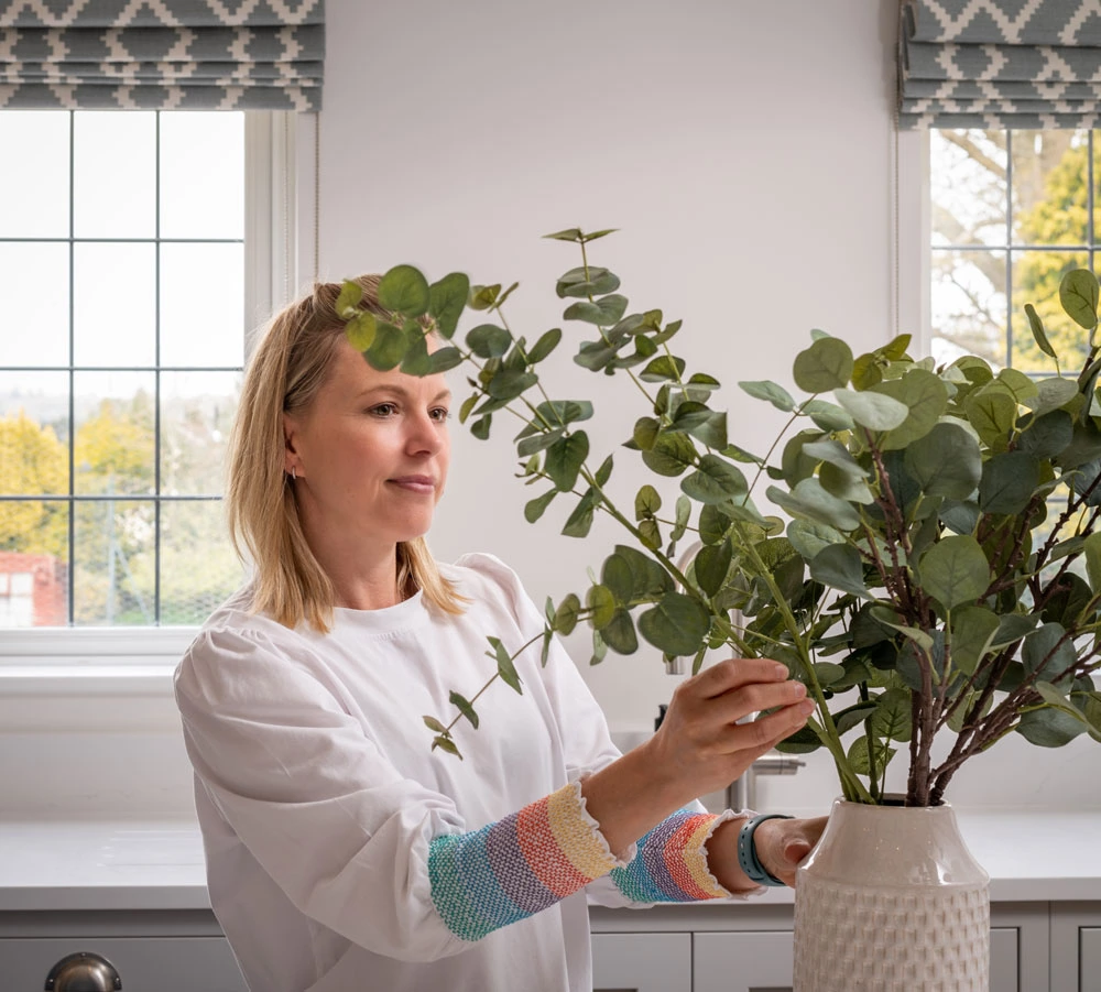 Georgie Hall of Interior Design by Georgie Hall arranging eucalyptus leaves in a vase in a bright and airy kitchen